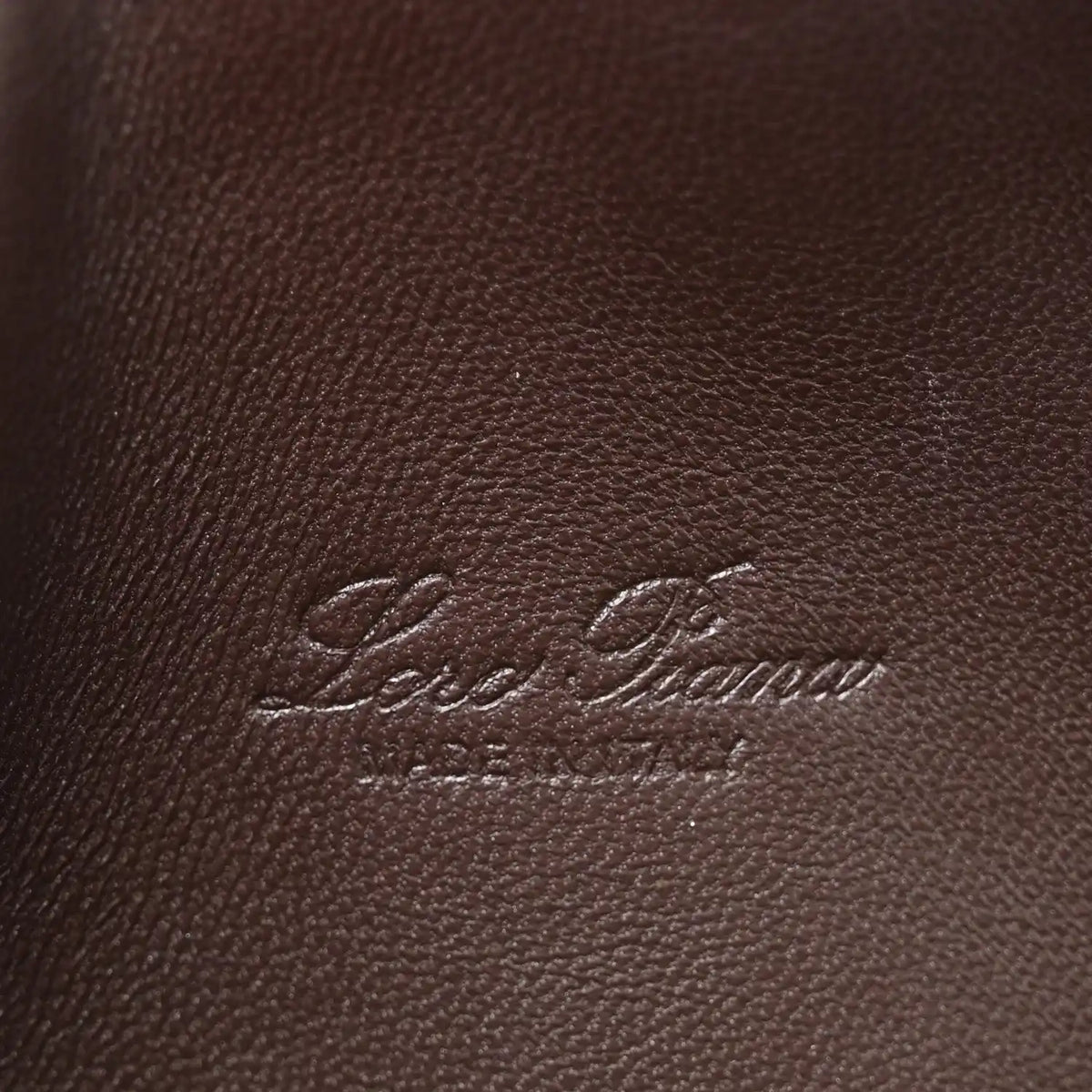 Loro Piana logo embossed on dark brown lizard leather pouch surface