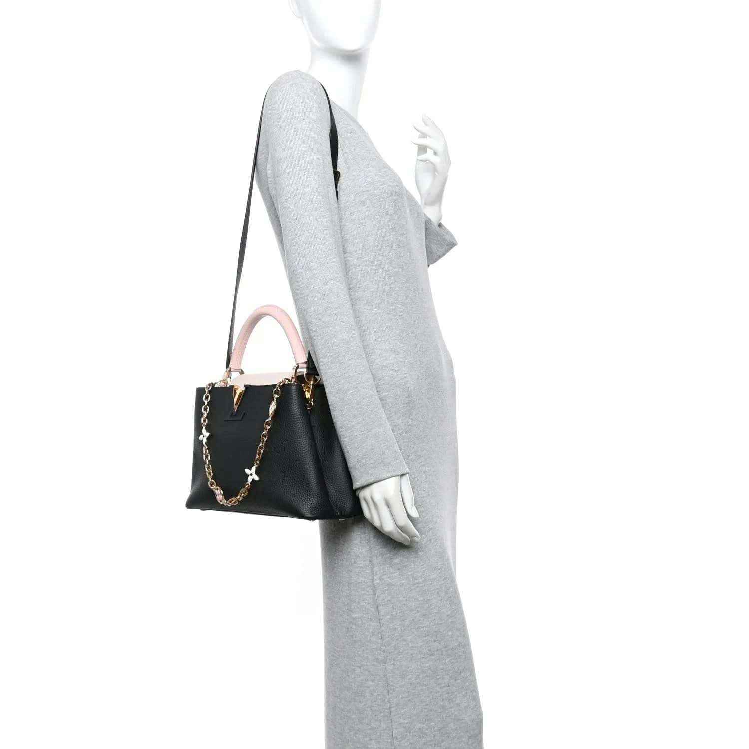 Black leather handbag with pink strap, worn on model arm
