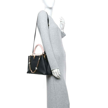 Black leather handbag with pink strap, worn on model arm