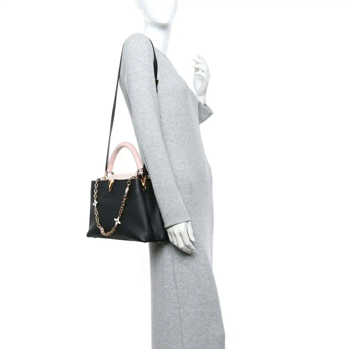 Black leather handbag with pink strap, worn on model arm