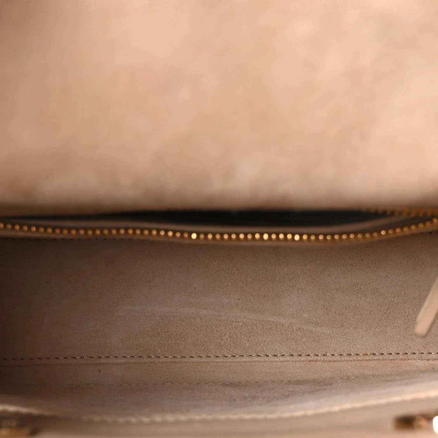 Beige handbag interior with zippered top opening and stitched edge