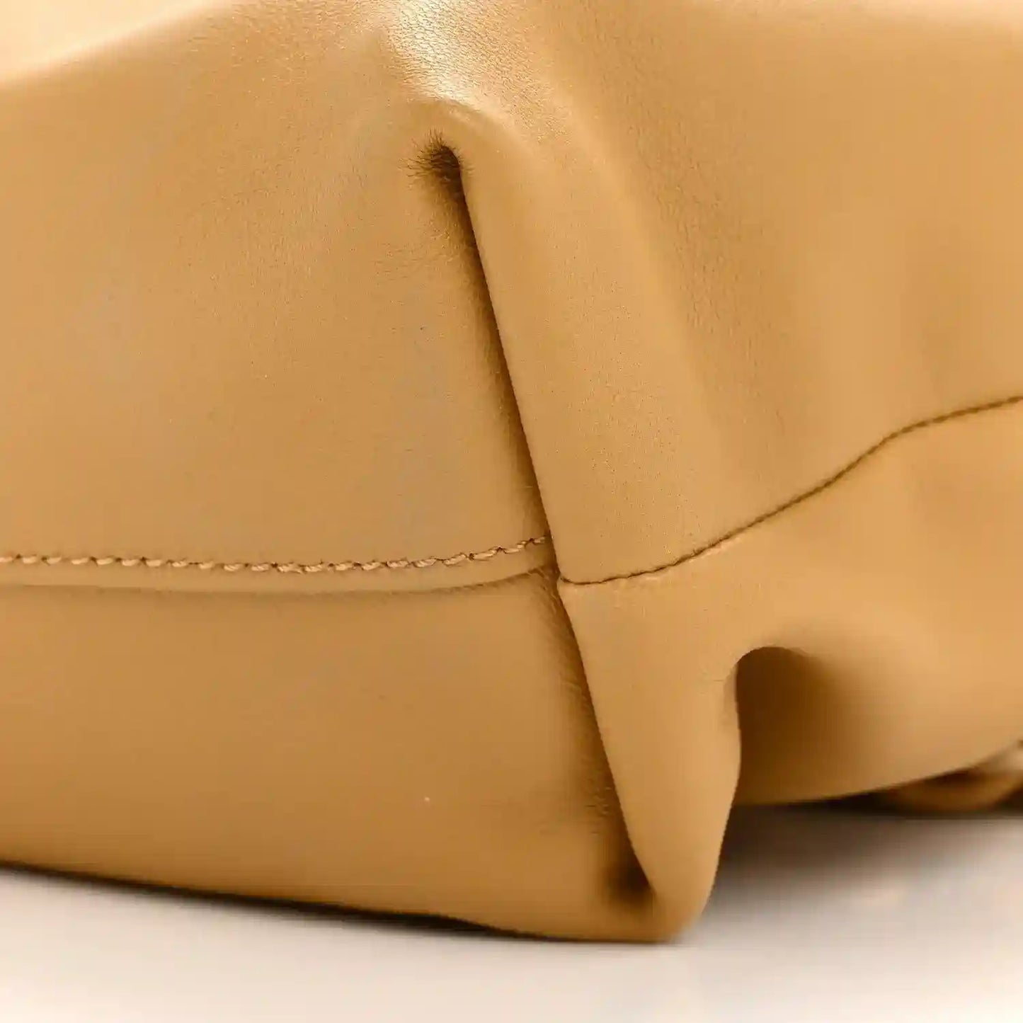 Tan leather clutch corner with seam stitching and small loop detail