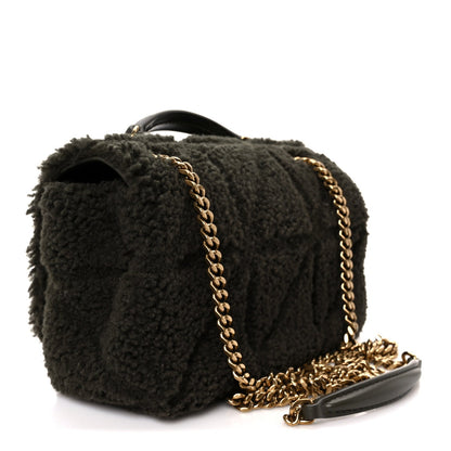 Dark shearling shoulder bag with gold chain strap and top handle, angled view