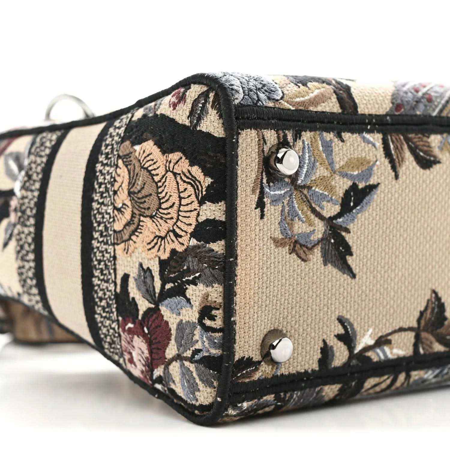 Floral embroidered canvas bag front with black trim, snap panel and stud hardware.