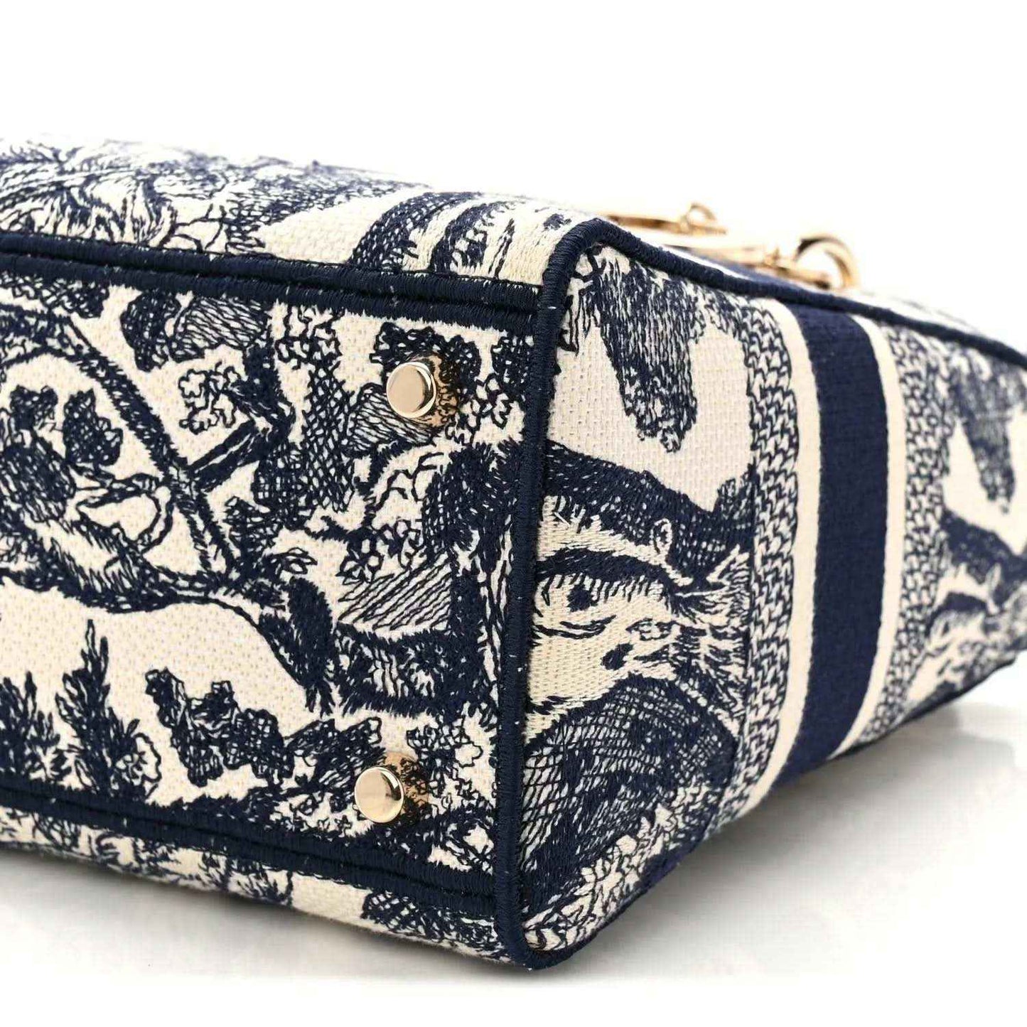 Blue toile de Jouy handbag end panel close-up with gold studs and navy piping.