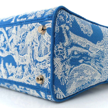 Blue embroidered handbag corner close-up with snap hardware and textured fabric.