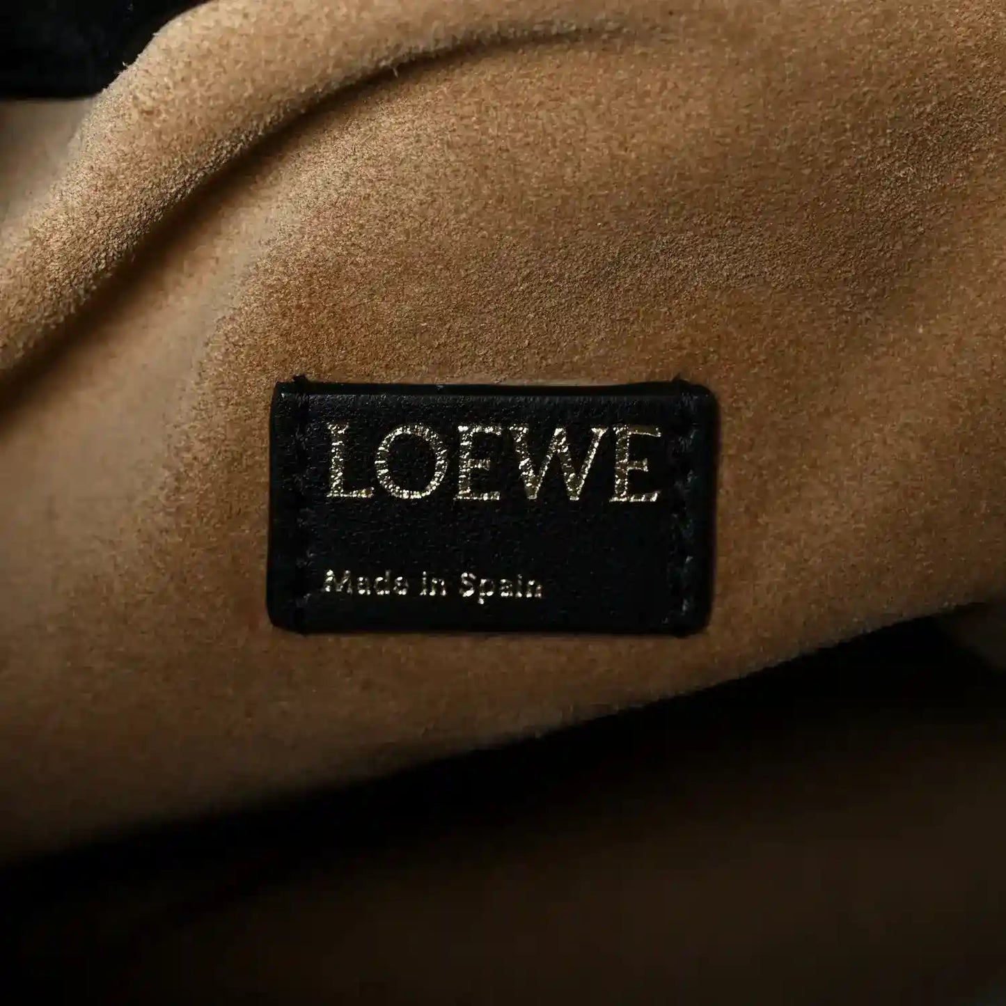Black leather clutch inner label with LOEWE branding and “Made in Spain” text.
