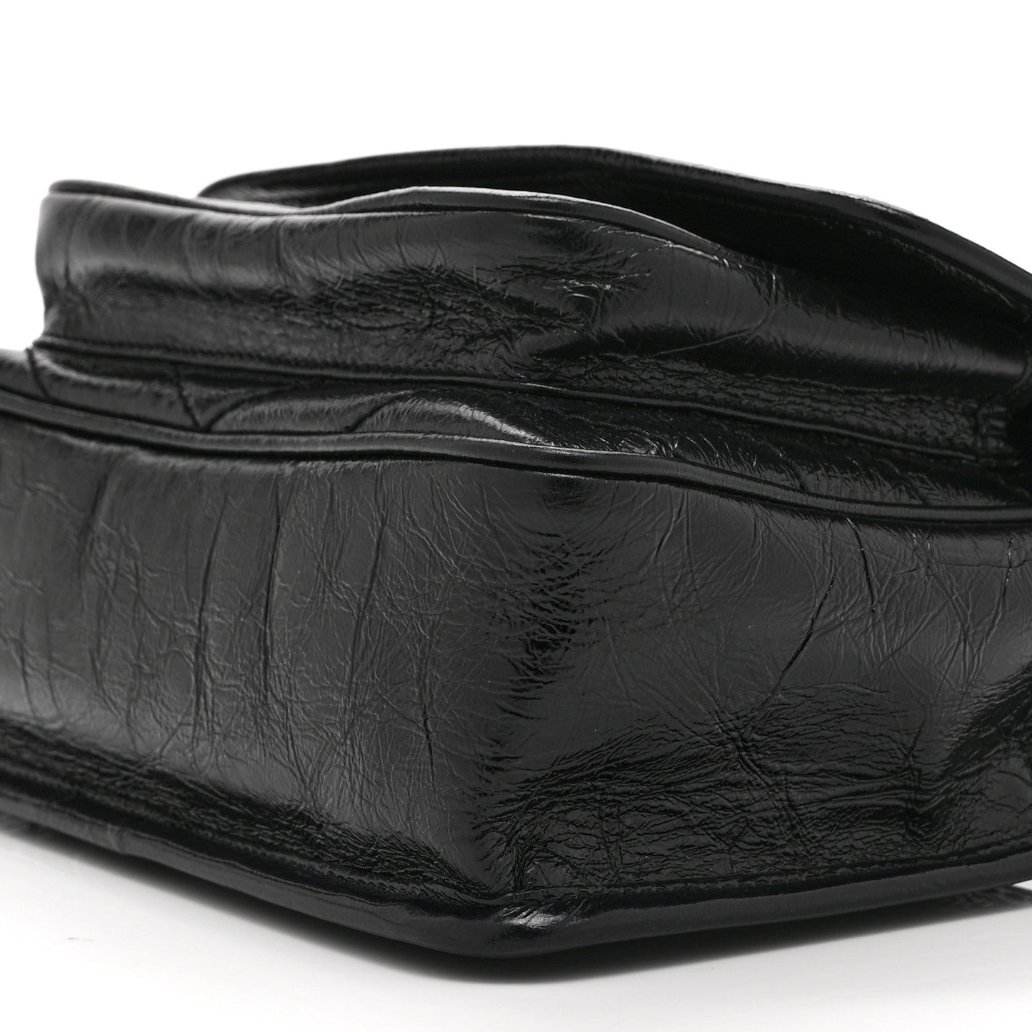 Black leather satchel bag close-up with crinkled finish and curved flap seam