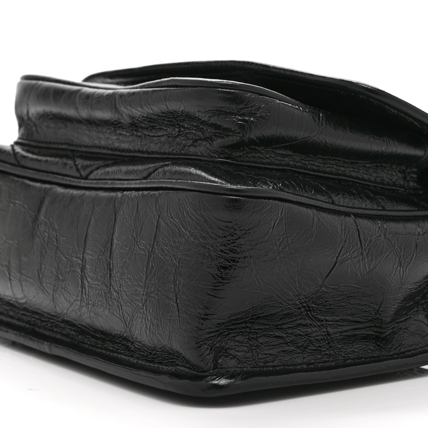 Black leather satchel bag close-up with crinkled finish and curved flap seam