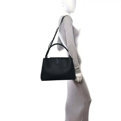 Black matte leather handbag worn at side with adjustable shoulder strap