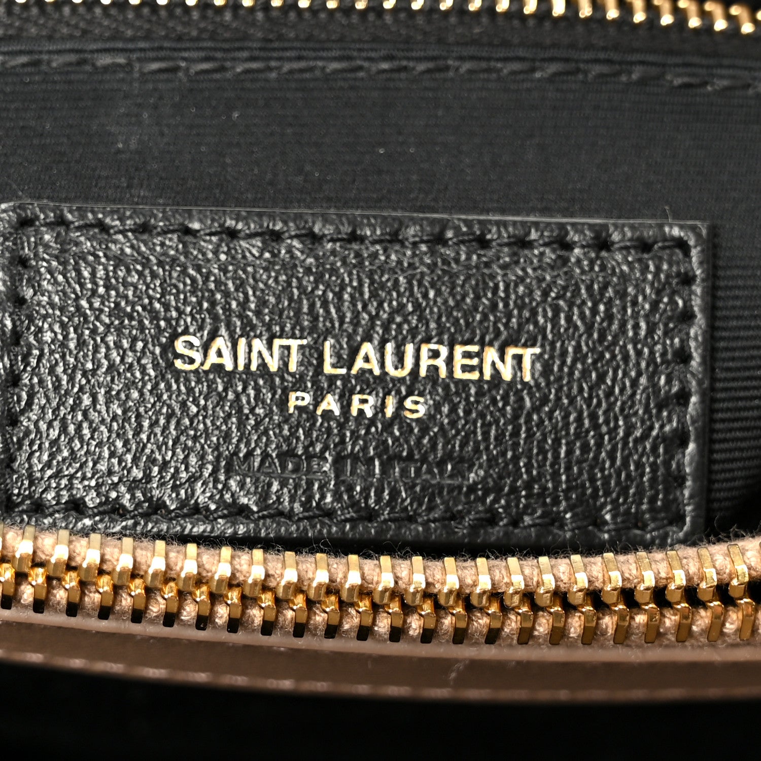 Black leather label with SAINT LAURENT PARIS text and gold zipper