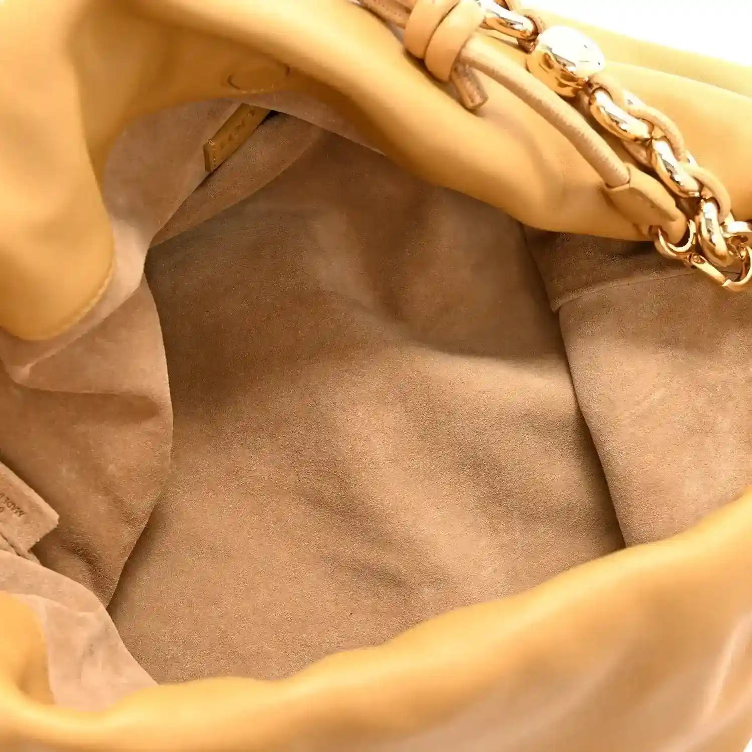 Tan suede-lined clutch interior with leather edges and chain hardware