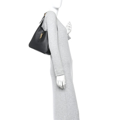 Black hobo handbag held at side, top handle and YSL logo on front panel.