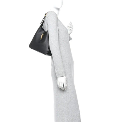 Black hobo handbag held at side, top handle and YSL logo on front panel.