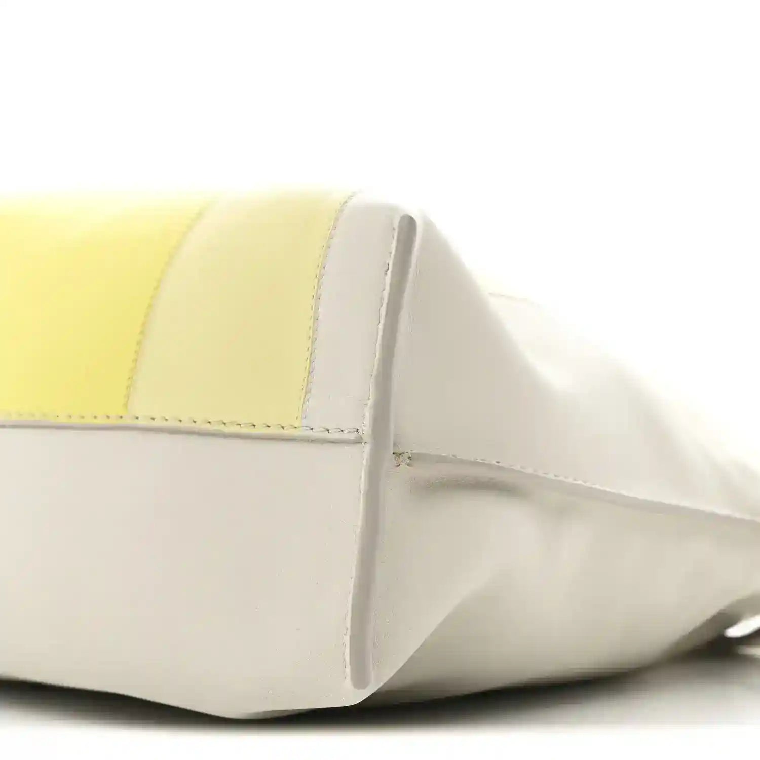 Close-up of pale grey and light citrine panels with curved front seam on clutch