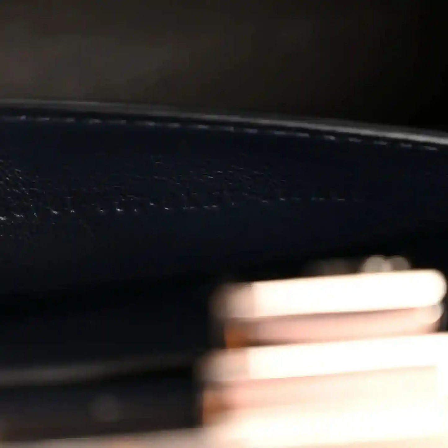 Close-up of stamped detail and fine stitching on dark nappa leather satchel