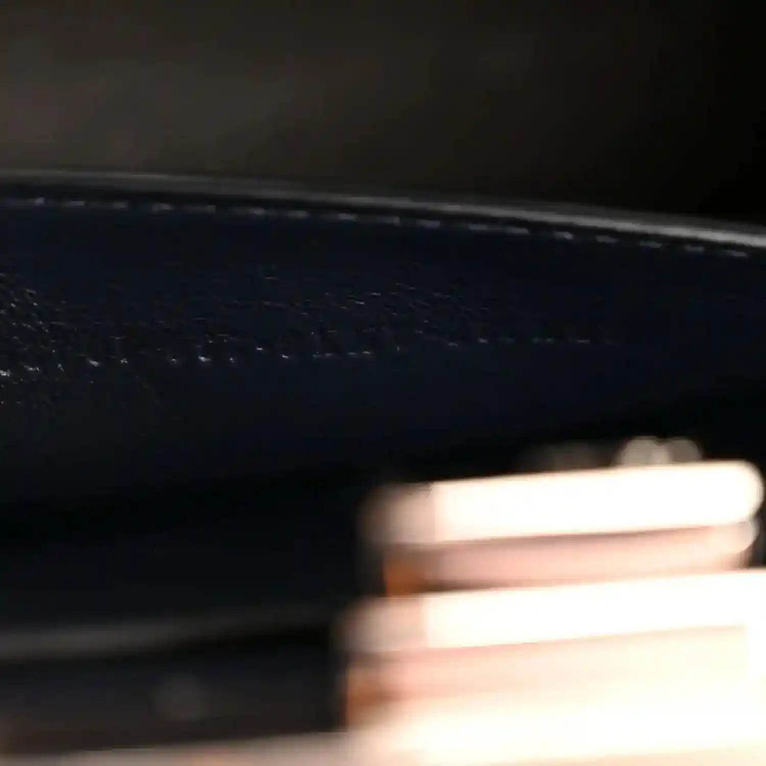 Close-up of stamped detail and fine stitching on dark nappa leather satchel