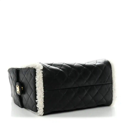 Black quilted leather handbag with white shearling trim and flap front