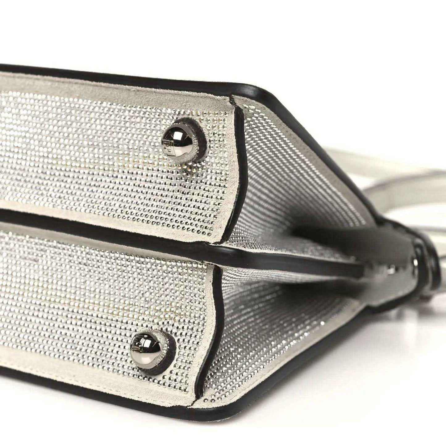 Small satchel bottom edge close-up with rivets, trim piping, and strap attachment