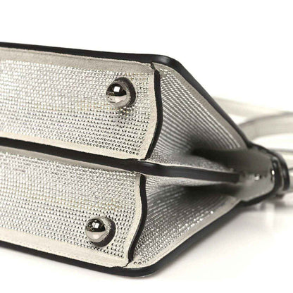 Small satchel bottom edge close-up with rivets, trim piping, and strap attachment