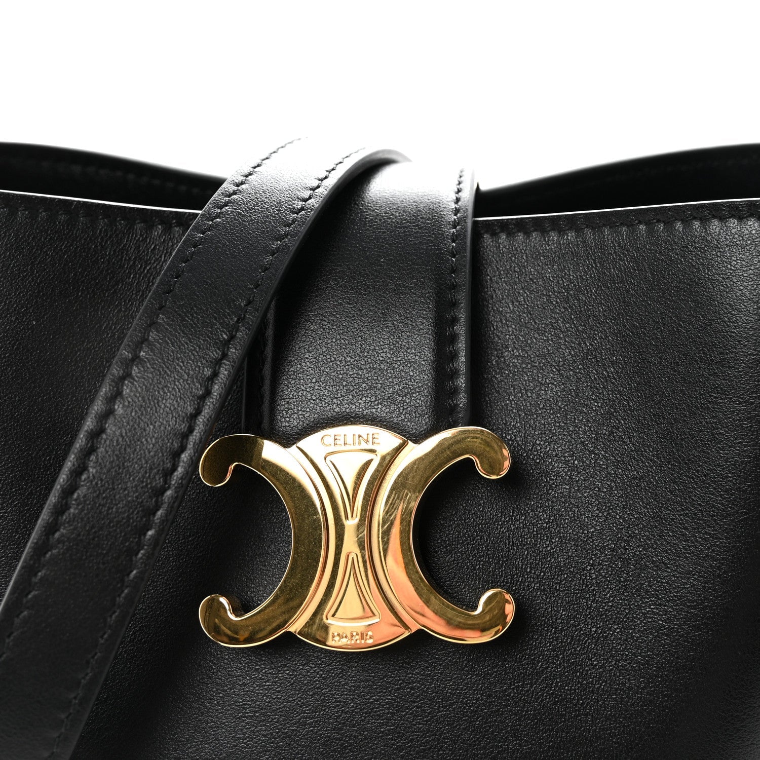 Close-up of gold Triomphe logo on black Celine leather with side handles