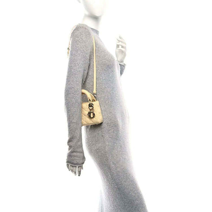 Soft yellow micro Lady Dior handbag worn crossbody with gold chain shoulder strap