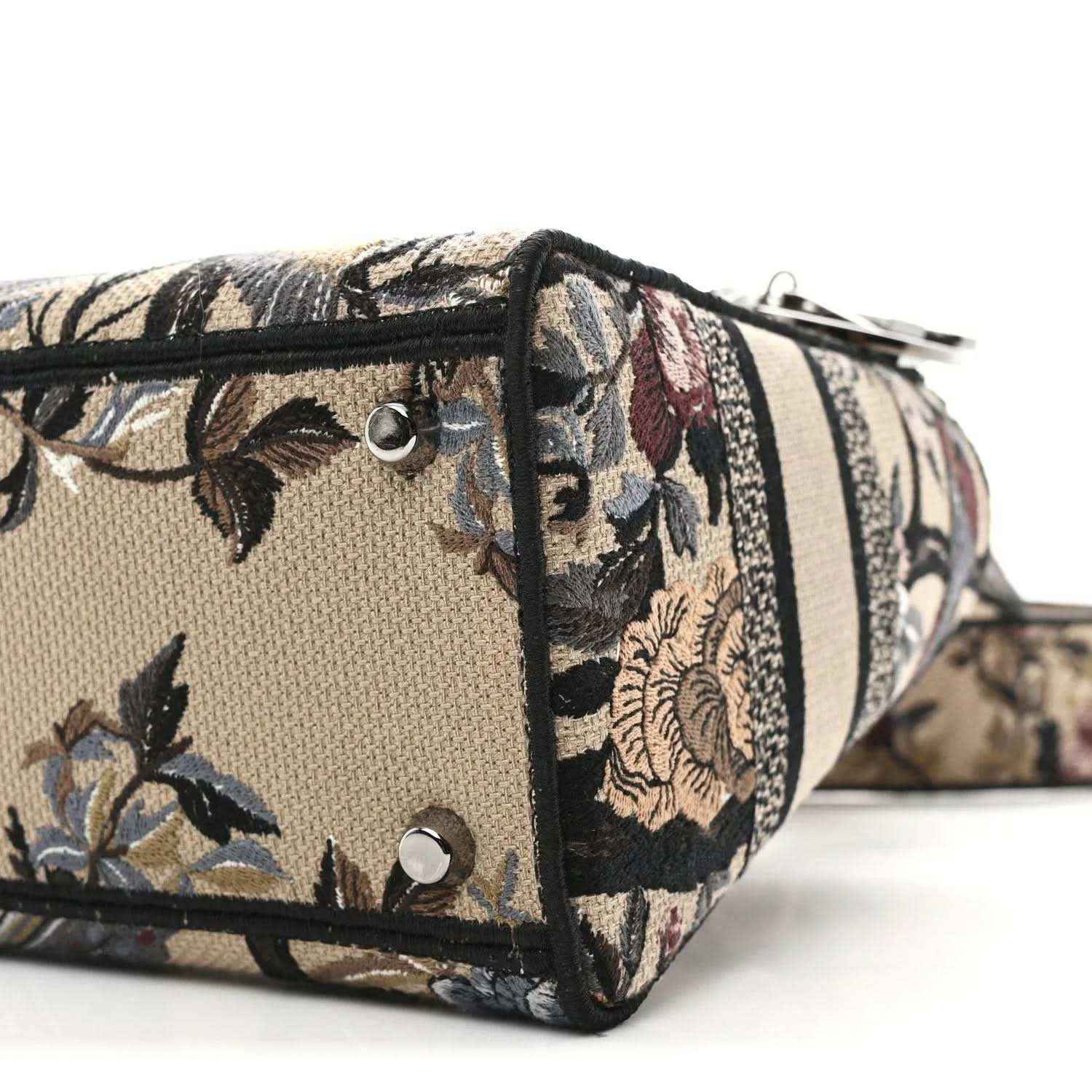 Floral canvas tote corner with silver studs and striped band, side profile.