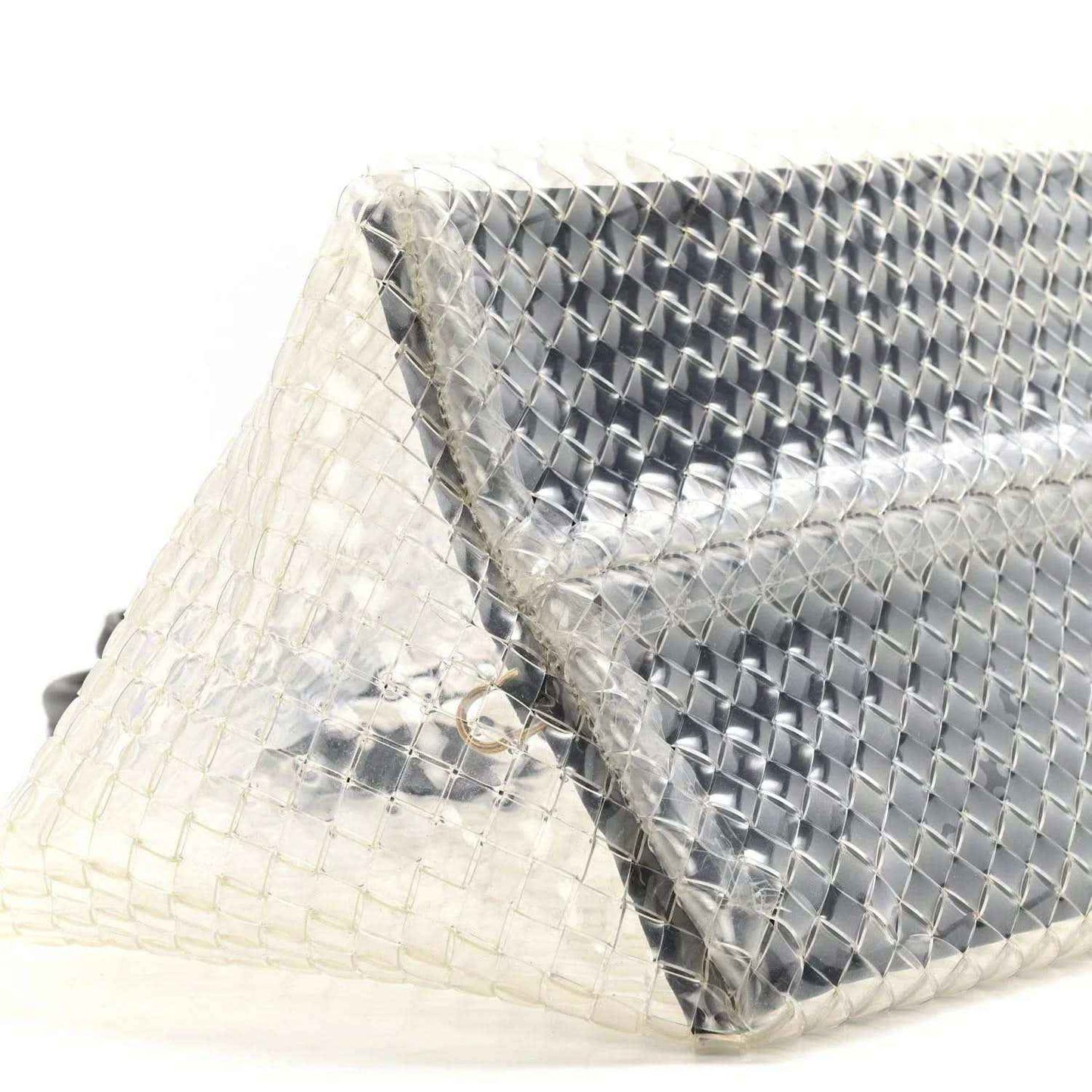 Close-up of woven PVC tote with silver-tone panel and black leather trim