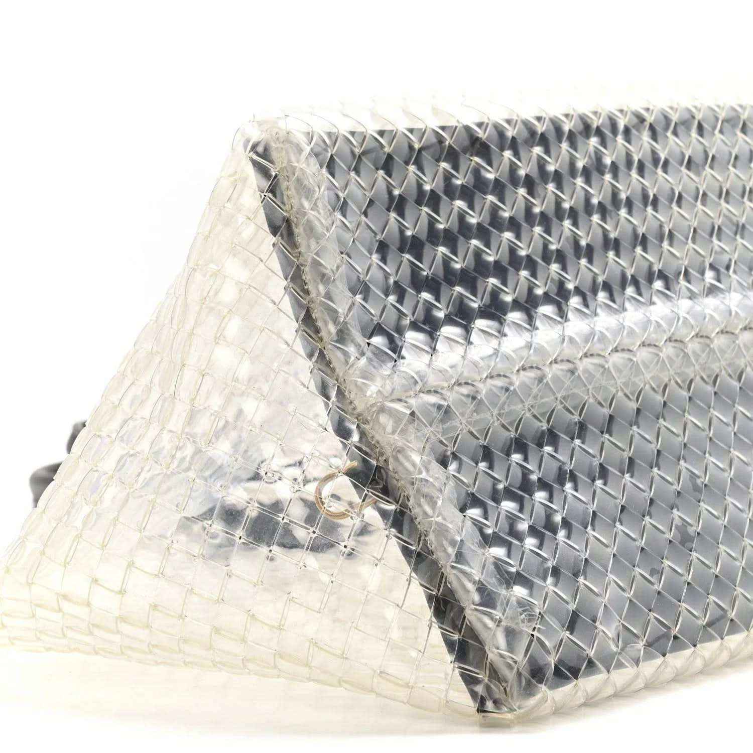 Close-up of woven PVC tote with silver-tone panel and black leather trim