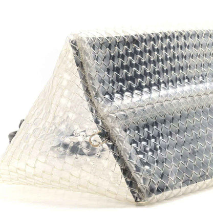 Close-up of woven PVC tote with silver-tone panel and black leather trim