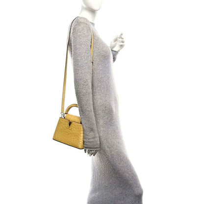 Yellow mini top-handle bag worn on shoulder, side view with single strap