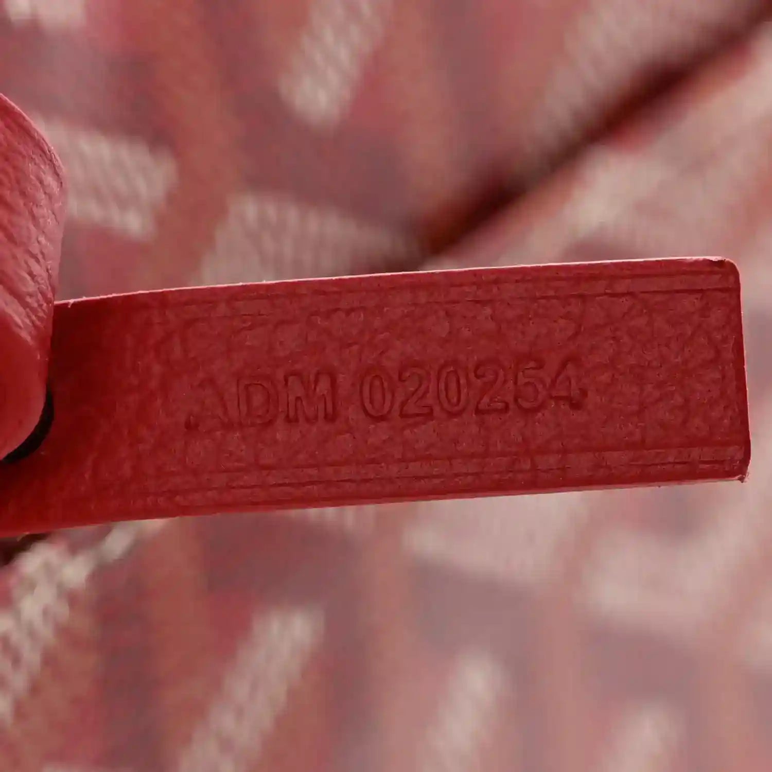 Red Goyardine leather label with stamped code details