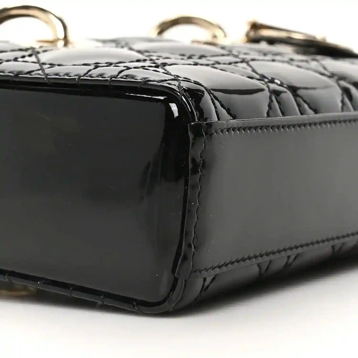 Black patent leather bag corner with quilting texture and edge stitching