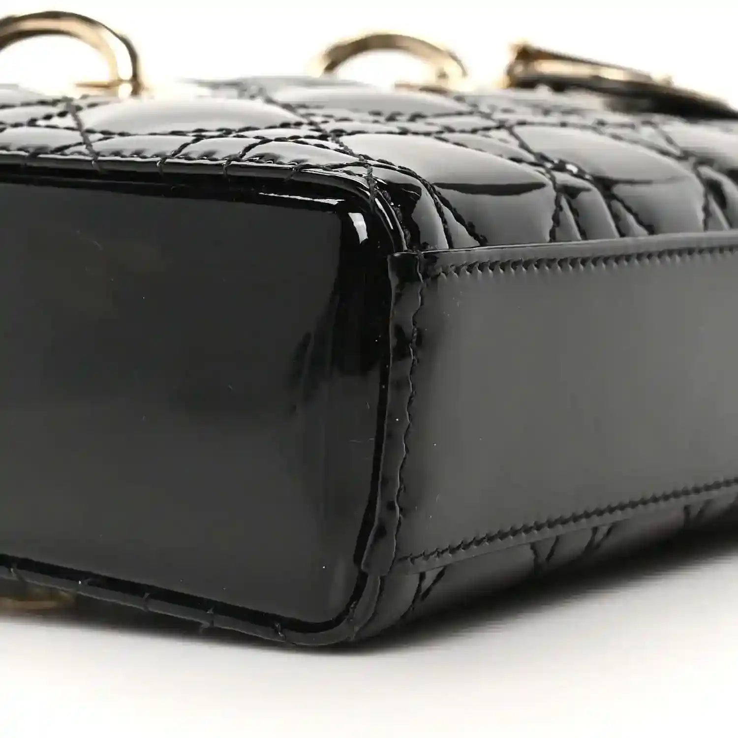 Black patent leather bag corner with quilting texture and edge stitching