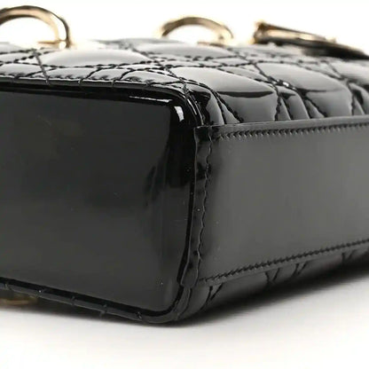 Black patent leather bag corner with quilting texture and edge stitching