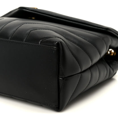 Black quilted leather satchel end with curved seam lines and top edge detail.