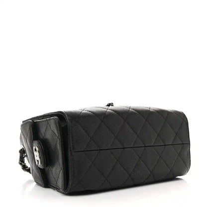 Black quilted mini shoulder bag with chain strap and structured top, side view.