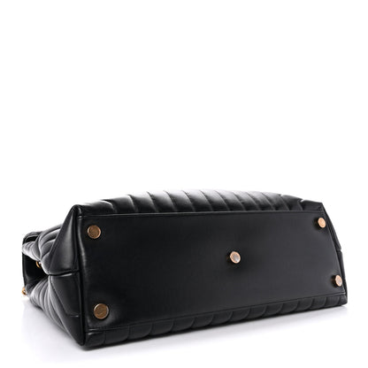 Black quilted satchel back with gold snap buttons and leather shoulder strap