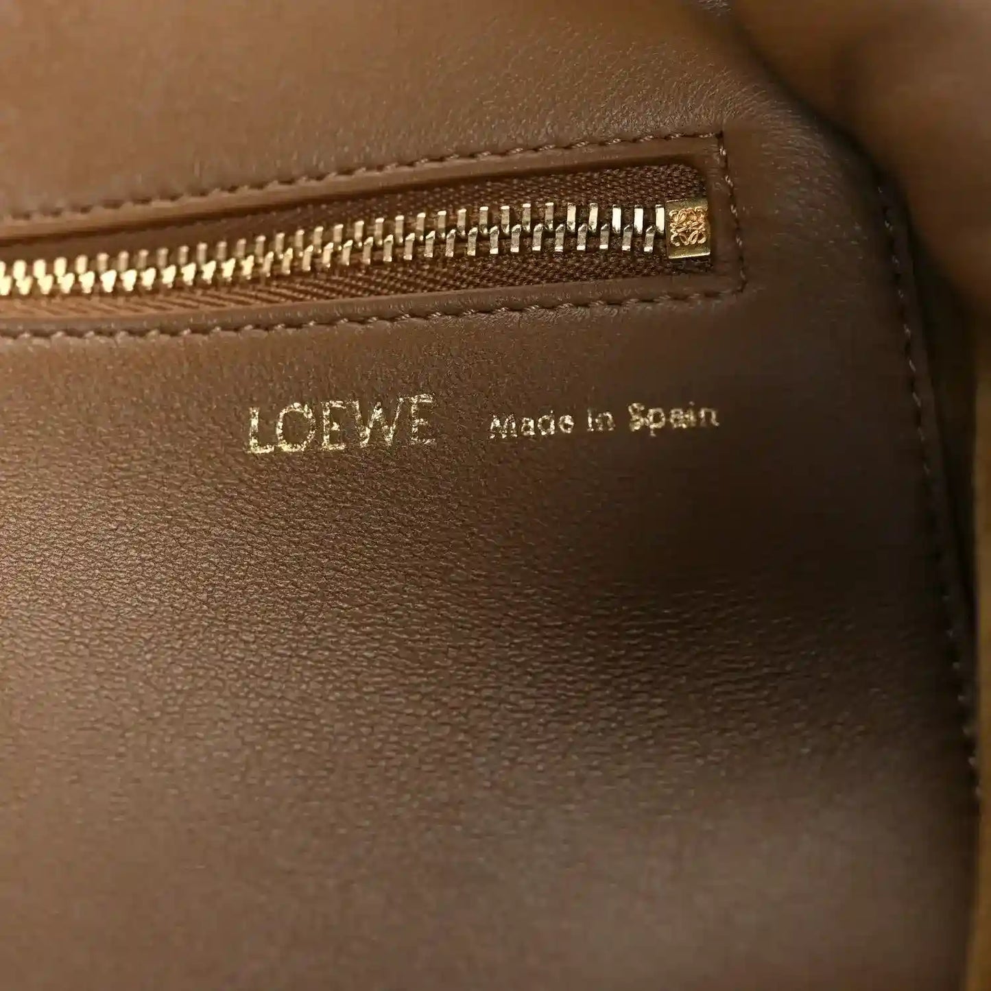 Loewe leather bag close-up of logo patch and gold zipper trim, oak brown