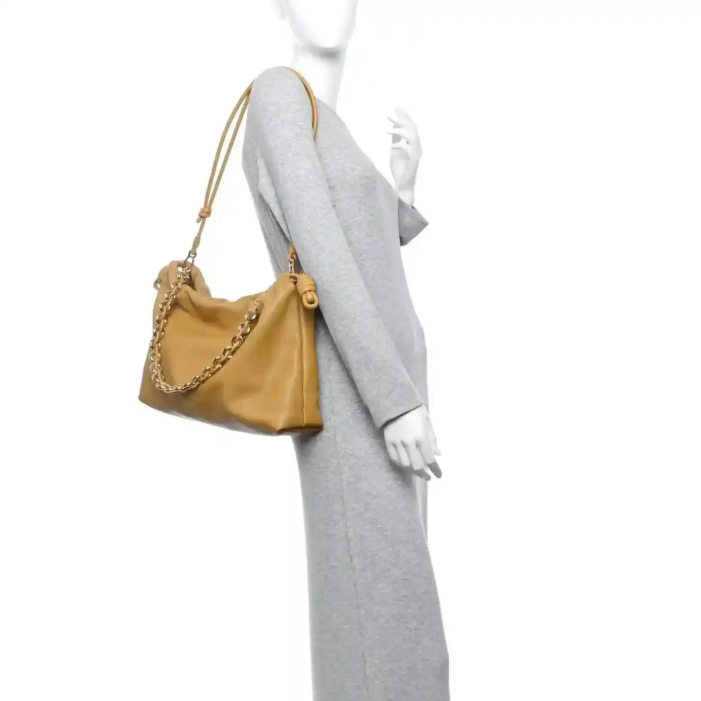 Tan leather clutch on model with chain strap draped over shoulder