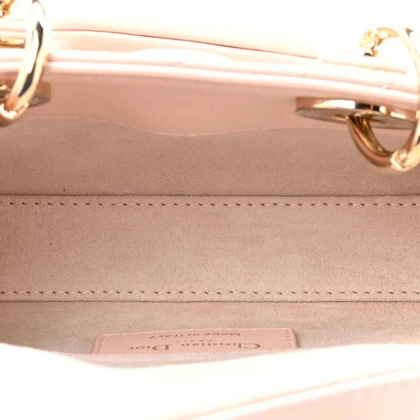Pink leather handbag interior with stitching and metal hardware on inner wall