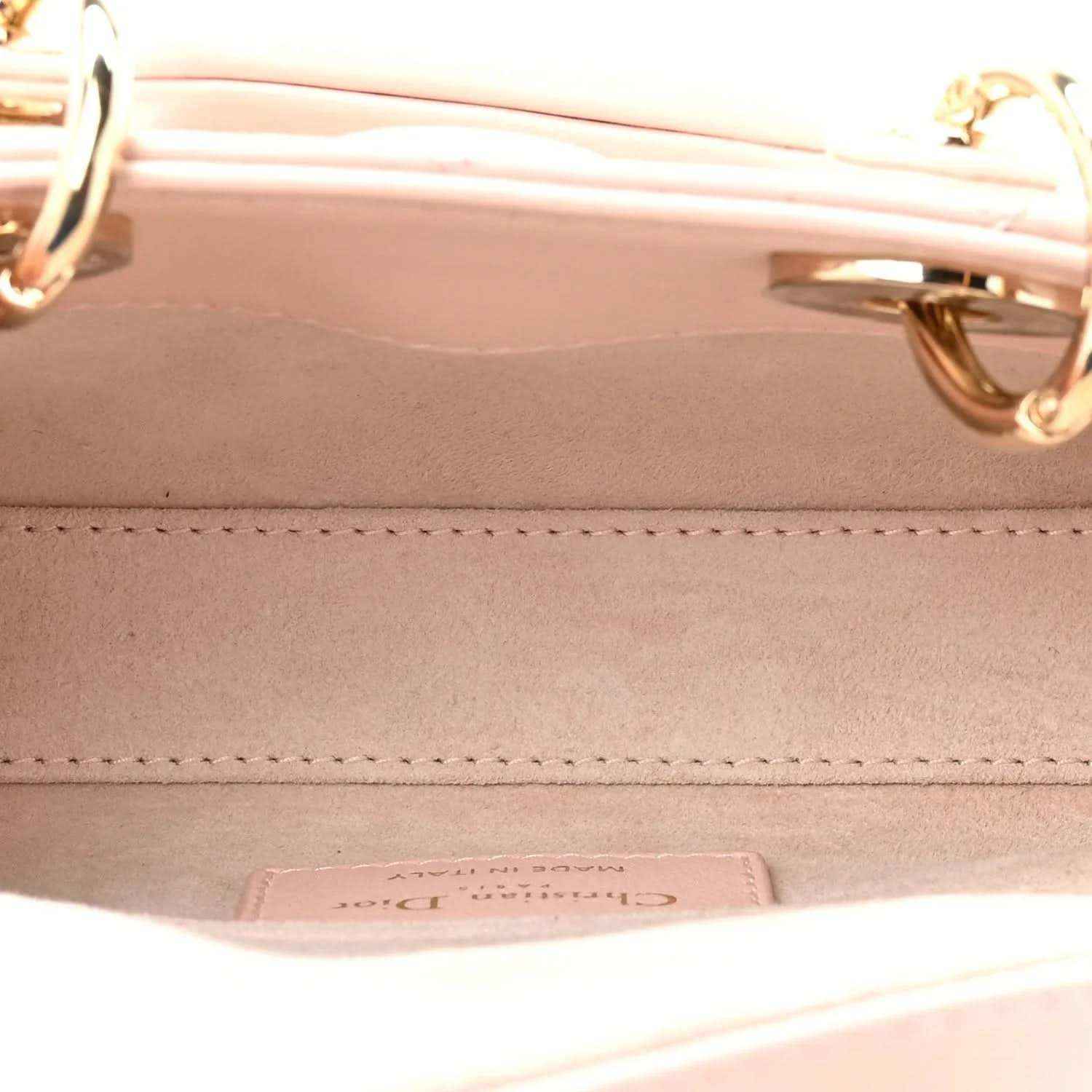 Pink leather handbag interior with stitching and metal hardware on inner wall