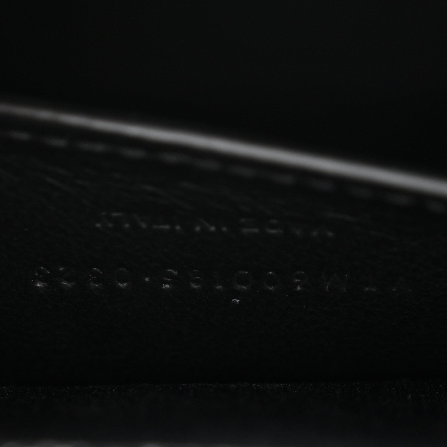 Black leather satchel bag detail with embossed grain texture near the seam