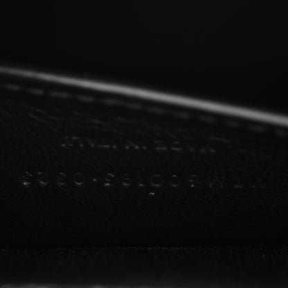 Black leather satchel bag detail with embossed grain texture near the seam