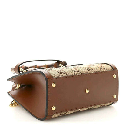 Mini tote bag side view with brown leather panel, gold studs, and bamboo handle