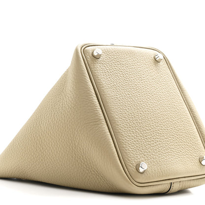 Beige leather handbag with metal corner studs and triangular silhouette