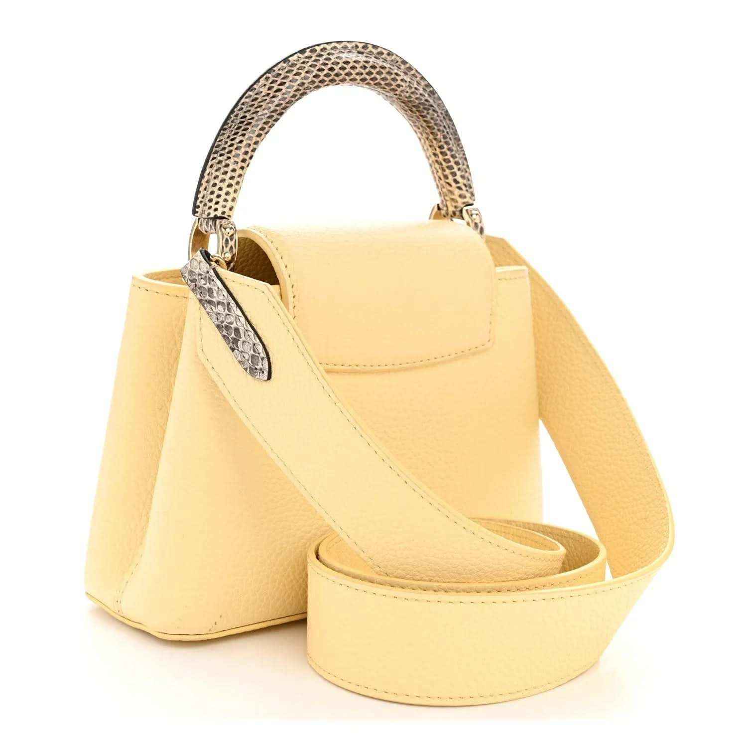Cream mini handbag with snakeskin handle trim and adjustable crossbody strap.