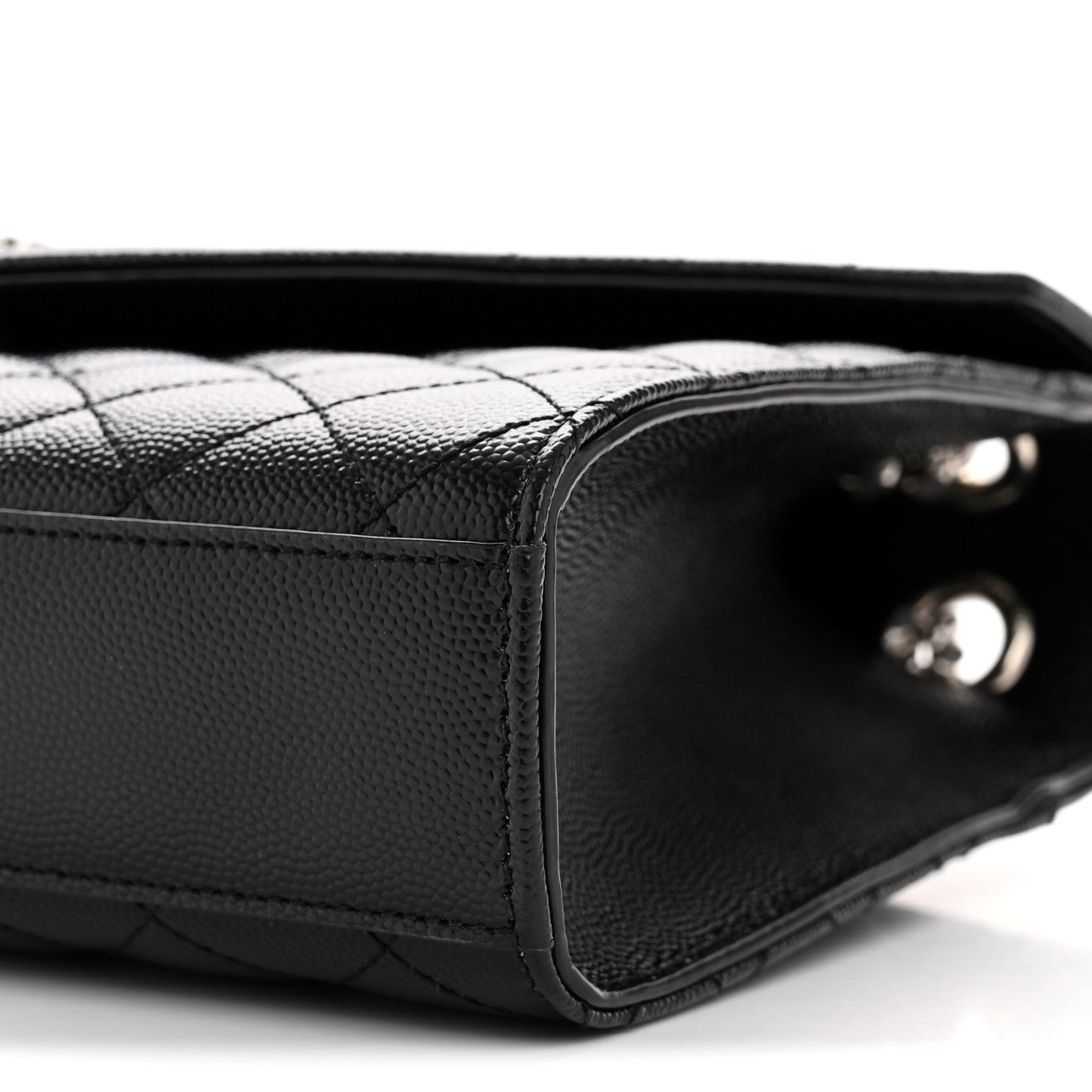 Black quilted satchel corner close-up with interior opening and metal studs