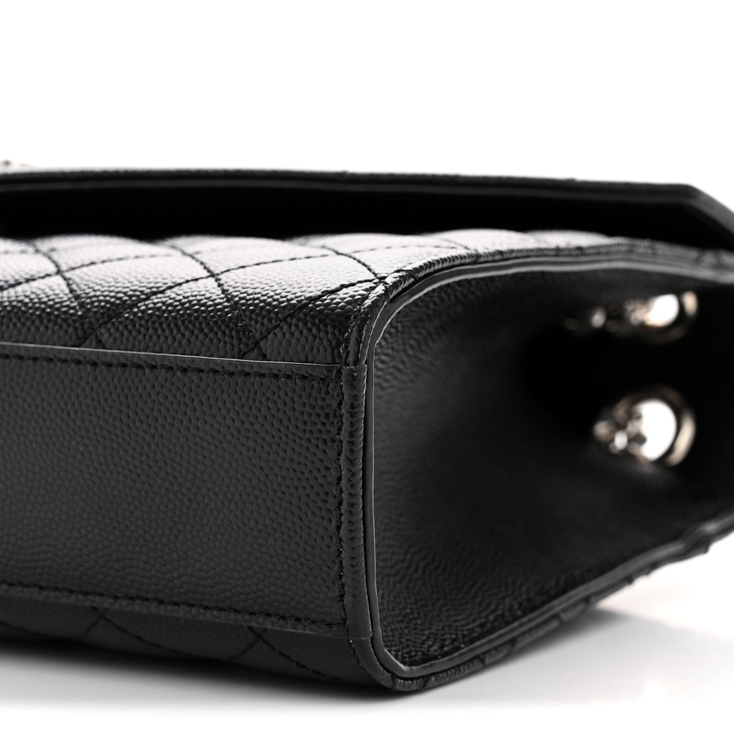 Black quilted satchel corner close-up with interior opening and metal studs