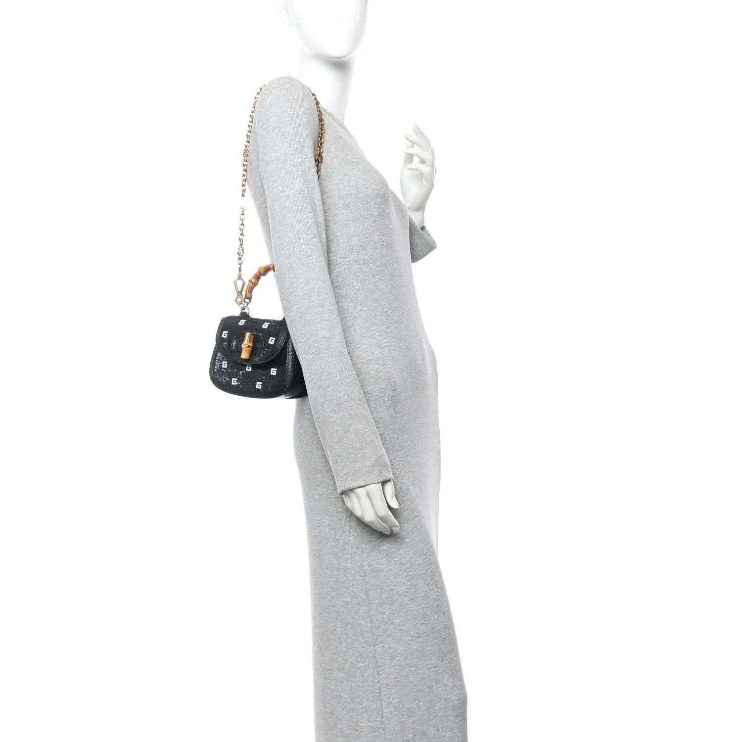 Black mini chain bag with gold chain strap, shown on a mannequin wearing a gray outfit